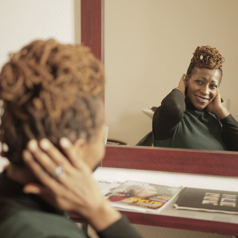 Femme aux Locks souriante face à son miroir dans un salon de coiffure