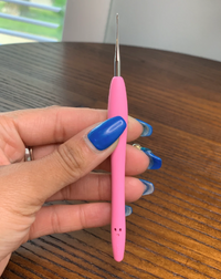 Aiguille crochet rose Locks Passion tenue par une main aux ongles bleus